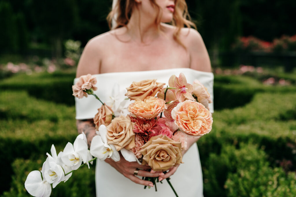 Leandra standing in the rose garden at The Andrews Farm holding a bouquet of flowers.