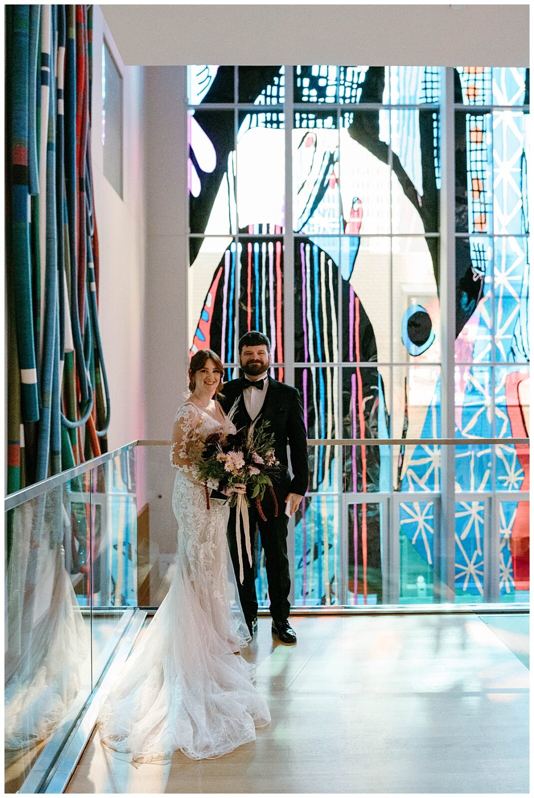 man and woman stand together in front of bright tapestry installation by The Hazel Club