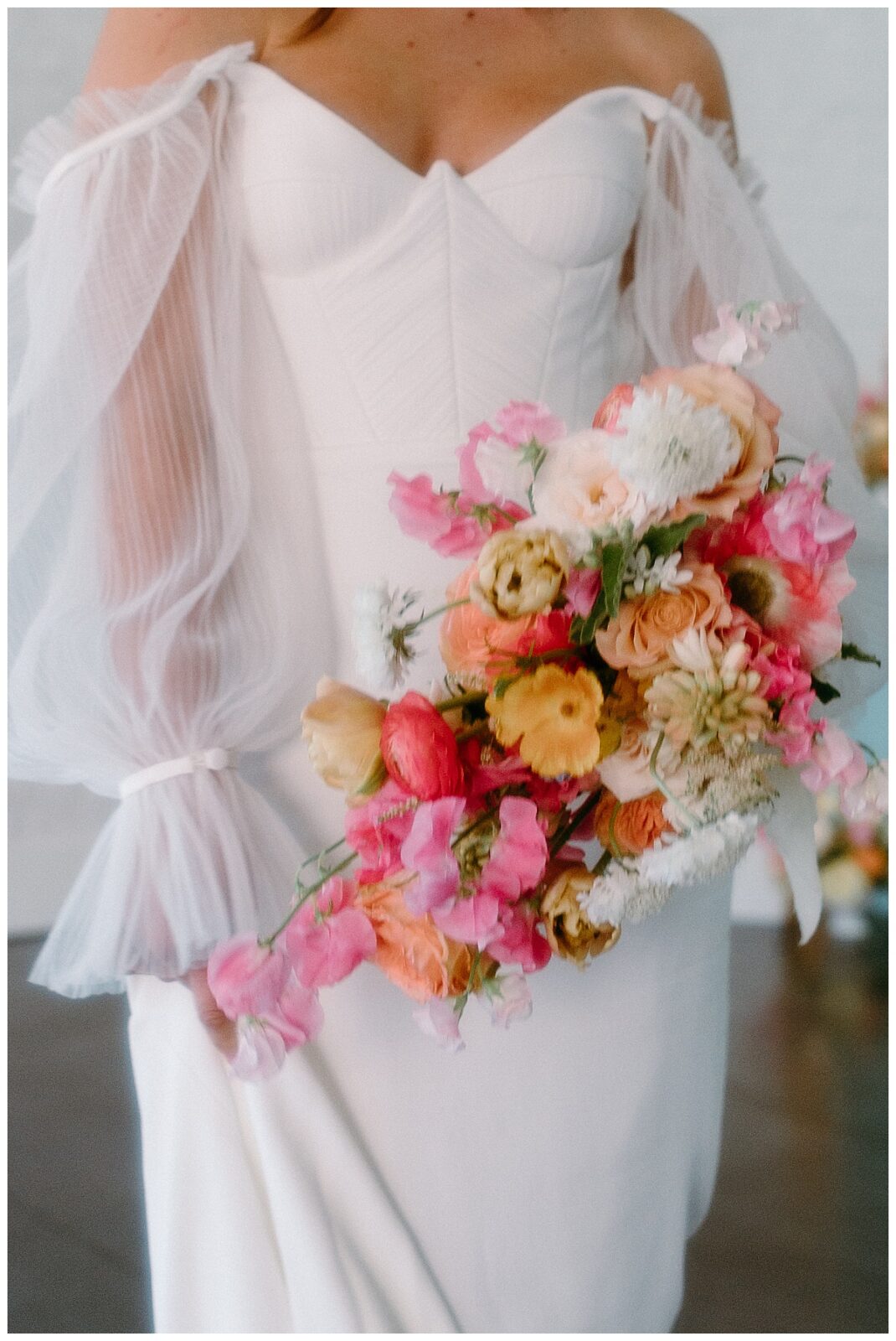 bride holds bouquet of pink and yellow flowers at Junction West styled shoot