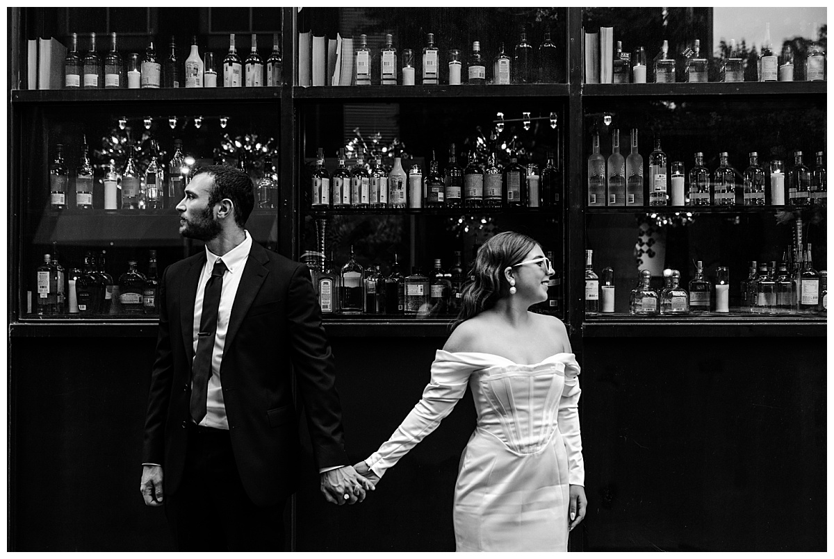 couple holds hands looking opposite directions during downtown engagement session