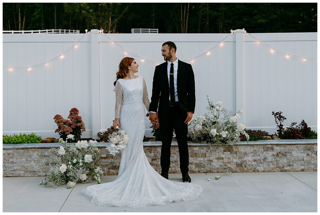 bride and groom hold hands and look at each other at modern barn ceremony