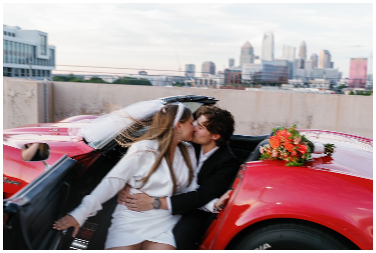 couple kisses in front seat of sports car during a rooftop session